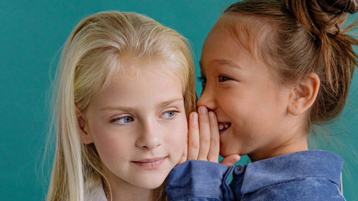 KW 20 Wochenend-Tipps mit Kindern: Was Familien an diesem Wochenende mit Kindern unternehmen können: Zwei Mädchen flüstern sich etwas zu // HIMBEER