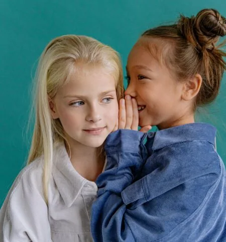 KW 20 Wochenend-Tipps mit Kindern: Was Familien an diesem Wochenende mit Kindern unternehmen können: Zwei Mädchen flüstern sich etwas zu // HIMBEER
